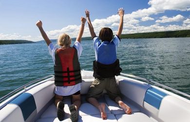 Two kids in the bow of a motorboat acting out a scene from the movie "Titanic".